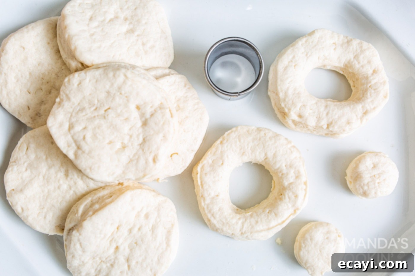 Air Fryer Donut Delights 7 Canned biscuits laid out, with some already cut into donut shapes and small centers reserved for donut holes.