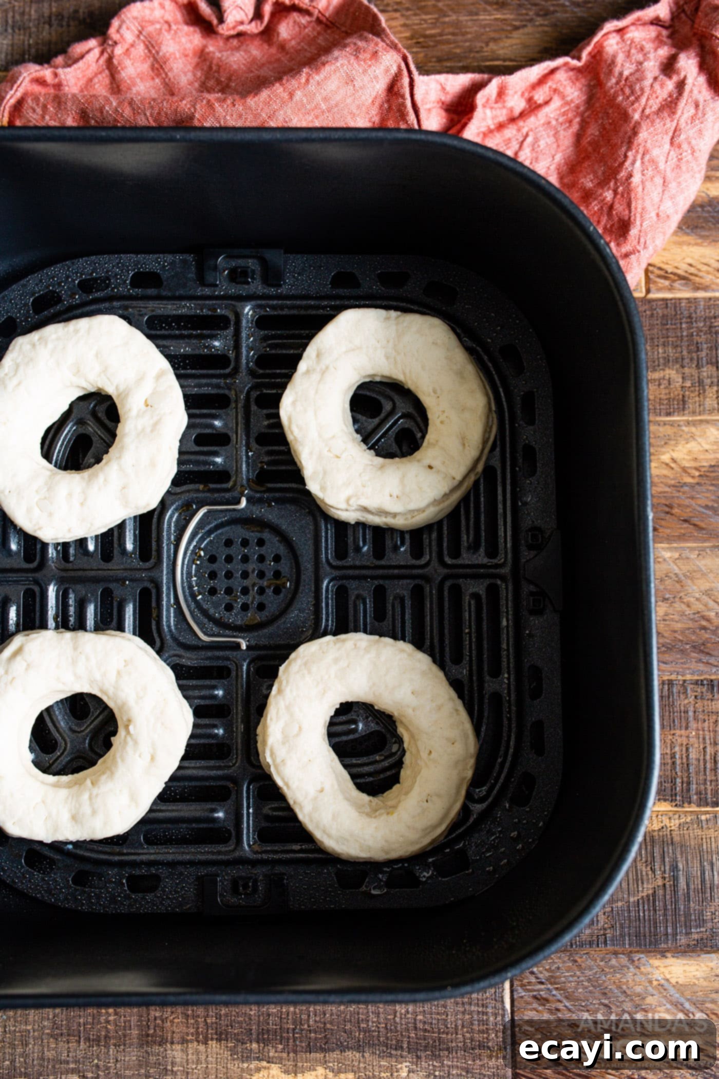 Air Fryer Donut Delights 8 Air fryer basket filled with biscuit donuts and donut holes, midway through cooking, showing light browning.
