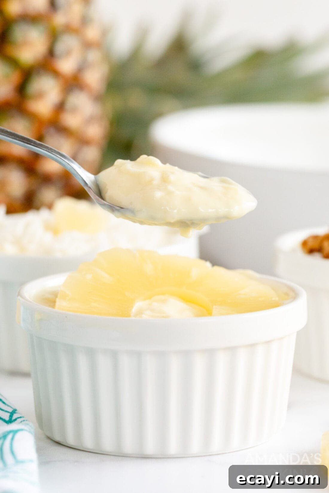 Golden Pineapple Yogurt Cloud 7 lifting spoon from pineapple yogurt dessert in a ramekin, showing creamy texture
