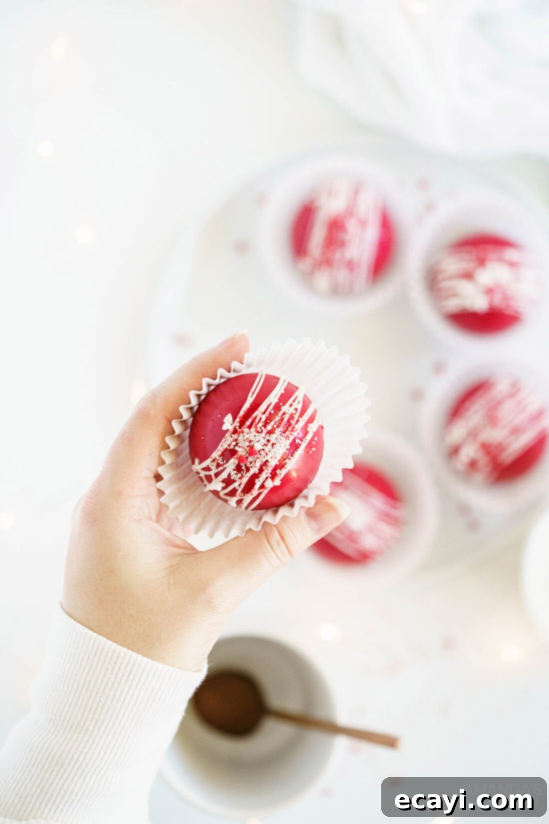Decadent Red Velvet Hot Cocoa Bombs 16 A woman holding a single red velvet cocoa bomb, perfectly formed and decorated, ready to be enjoyed or gifted.