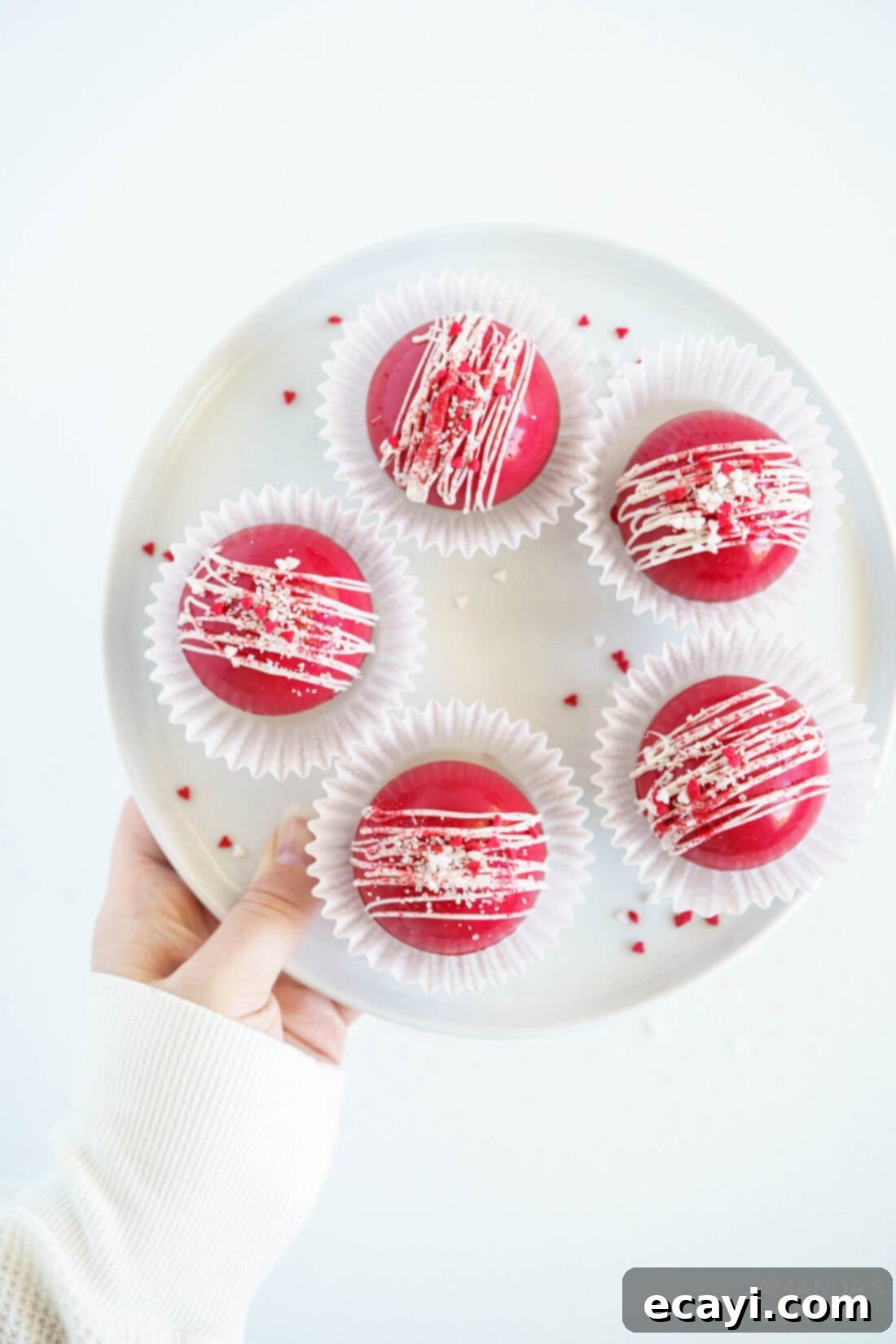 Decadent Red Velvet Hot Cocoa Bombs 3 A plate showcasing several finished red velvet cocoa bombs nestled in white paper liners, ready for gifting or serving.