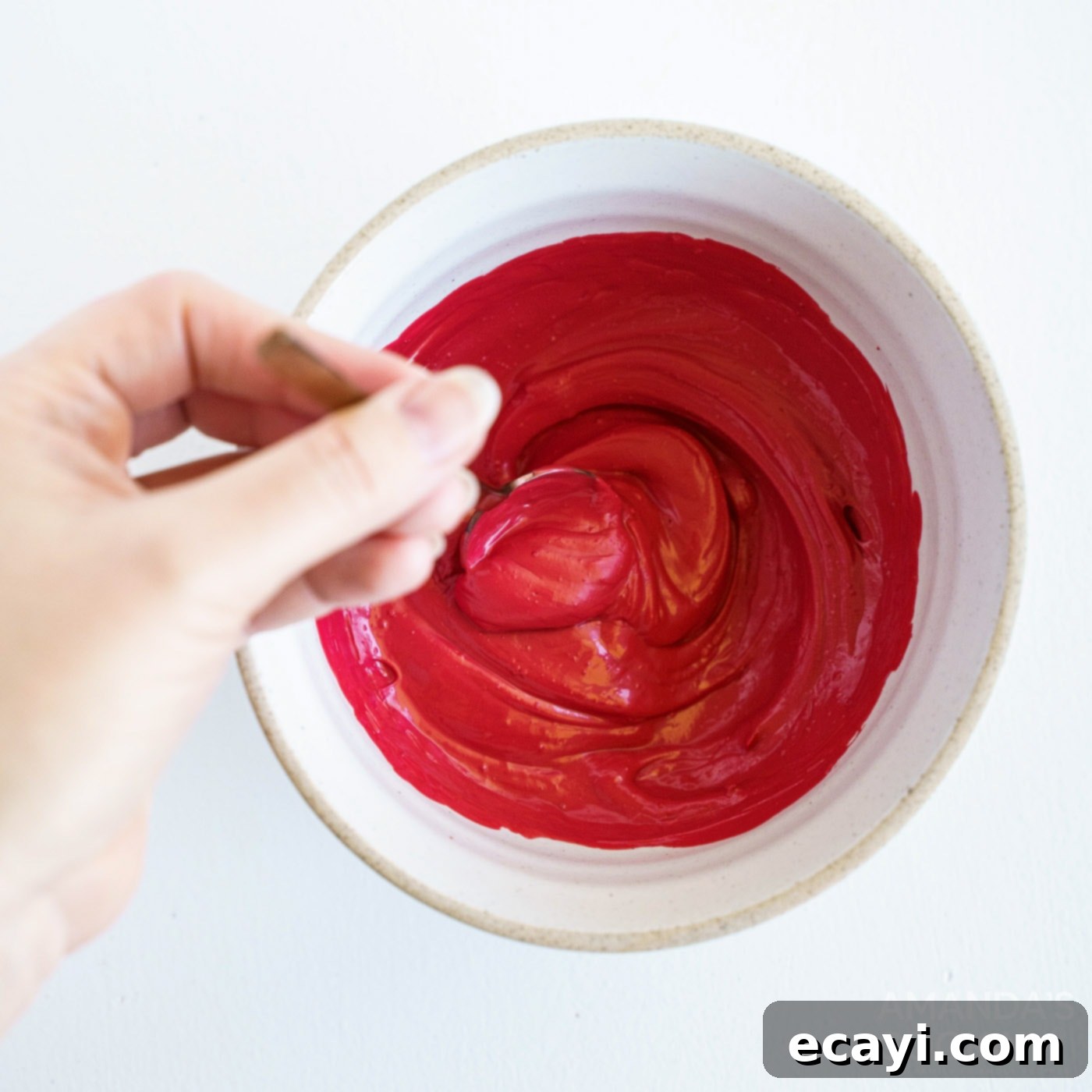 Decadent Red Velvet Hot Cocoa Bombs 5 A close-up shot of red candy melts being stirred in a bowl set over a double boiler, showing the smooth, melted consistency.