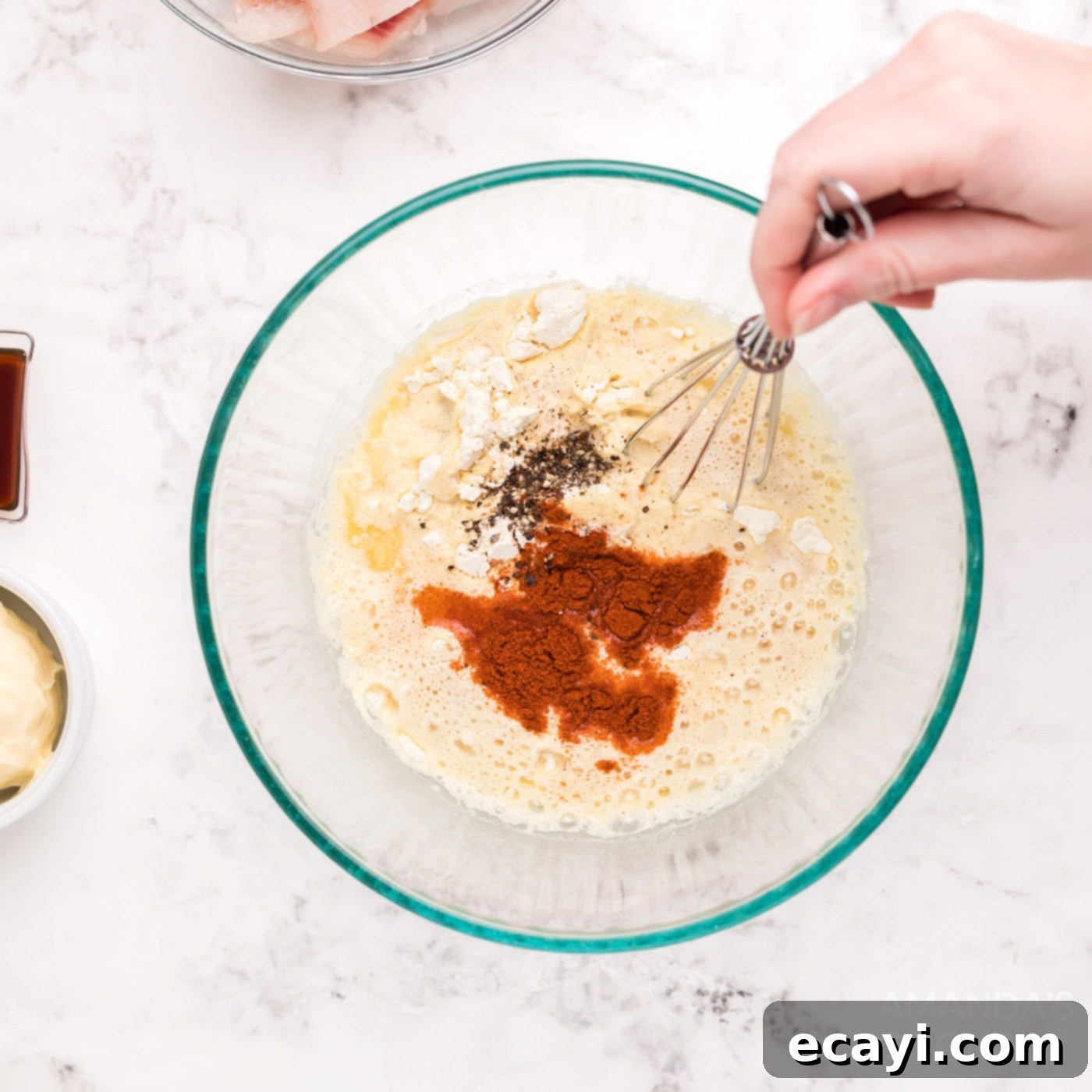 Crispy Golden Beer-Battered Fish 7 A whisk blending spices like pepper, salt, and paprika into a wet beer batter mixture in a mixing bowl.