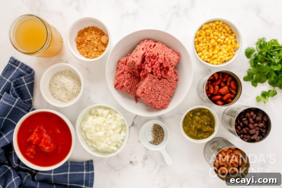 Fiesta Taco Soup 4 A flat lay of fresh and canned ingredients for making taco soup, including ground beef, onions, beans, corn, tomatoes, and seasoning packets.
