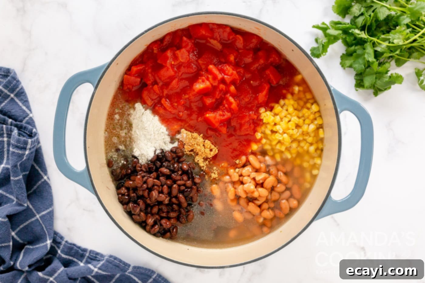 Fiesta Taco Soup 7 All the taco soup ingredients including chiles, beans, broth, seasoning, corn, and diced tomatoes added to the browned beef and onion in a large pot.