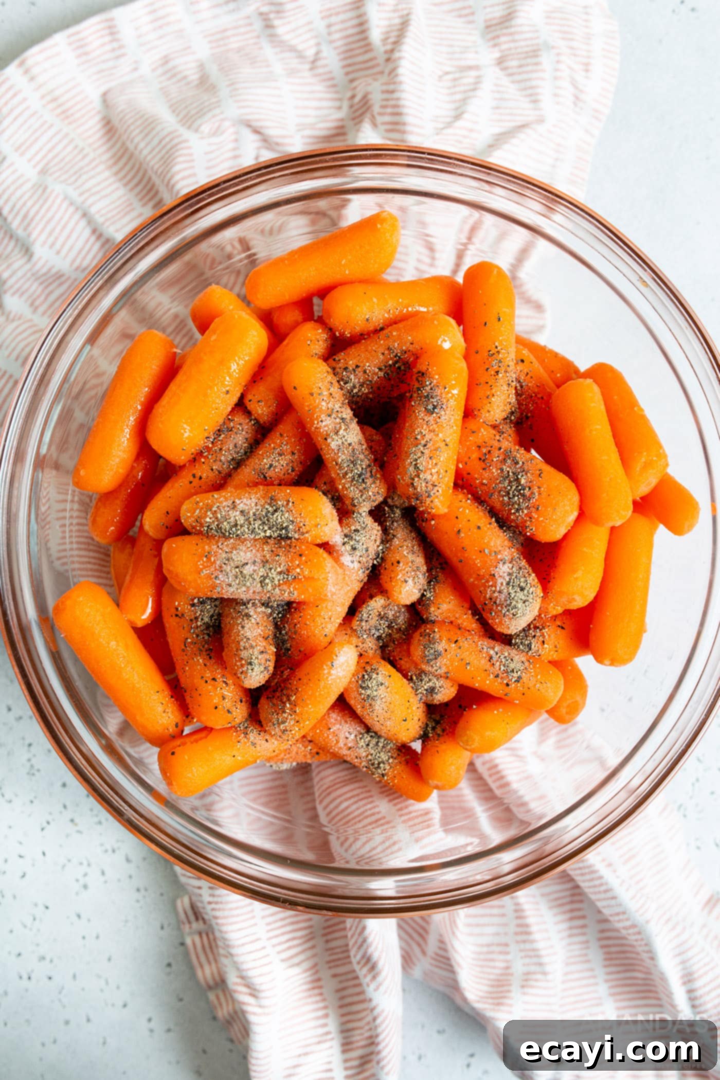 Golden Air Fryer Carrots 5 Carrots tossed with oil and seasonings in a large mixing bowl, ready for the air fryer.