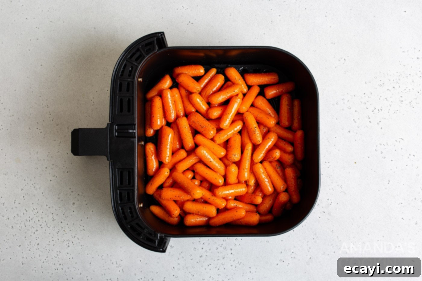Golden Air Fryer Carrots 6 Seasoned carrots loaded into a single layer within an air fryer basket, ready for cooking.
