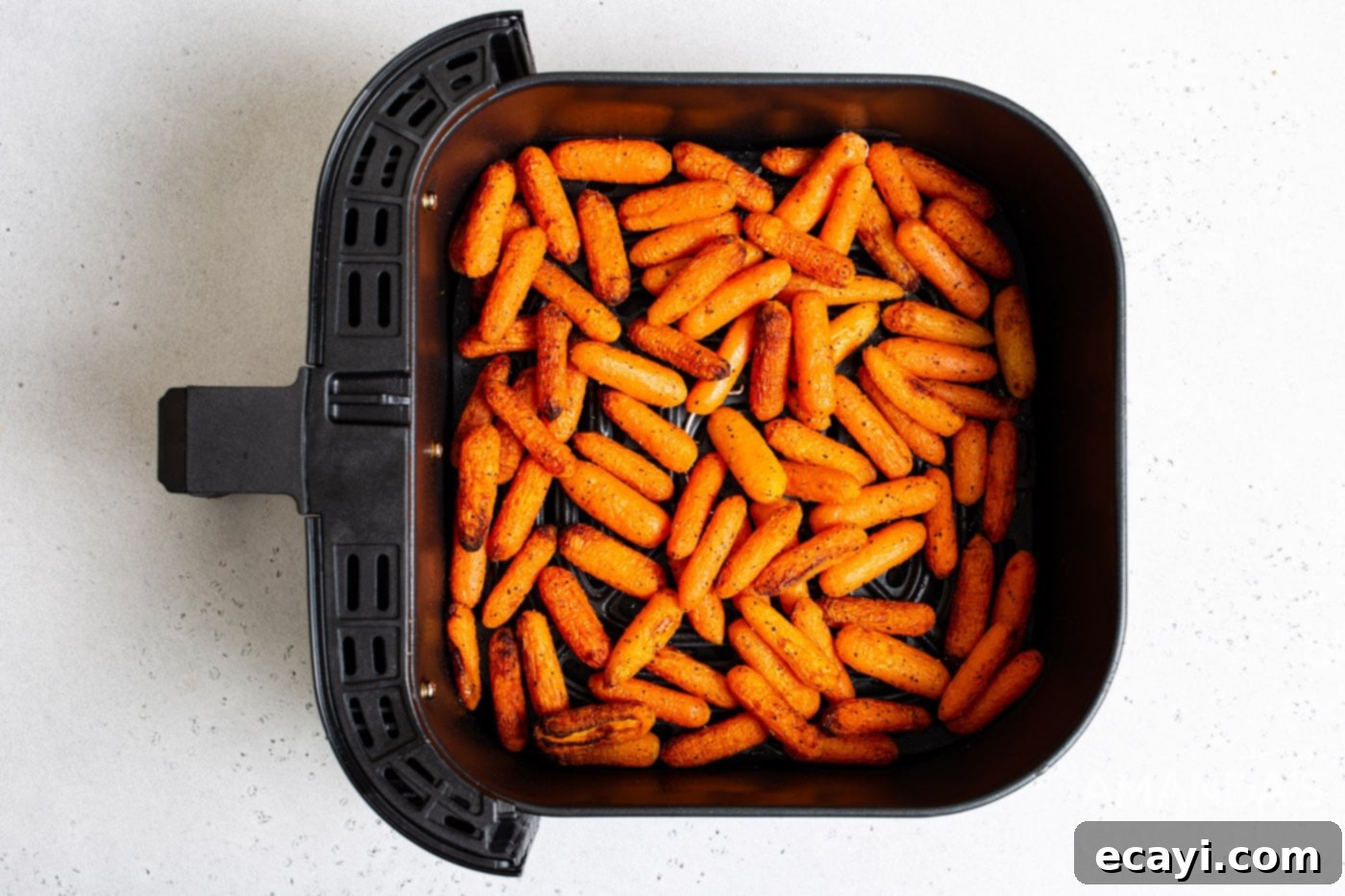 Golden Air Fryer Carrots 7 Cooked air fryer carrots in the air fryer basket, garnished with shredded parmesan and fresh parsley.