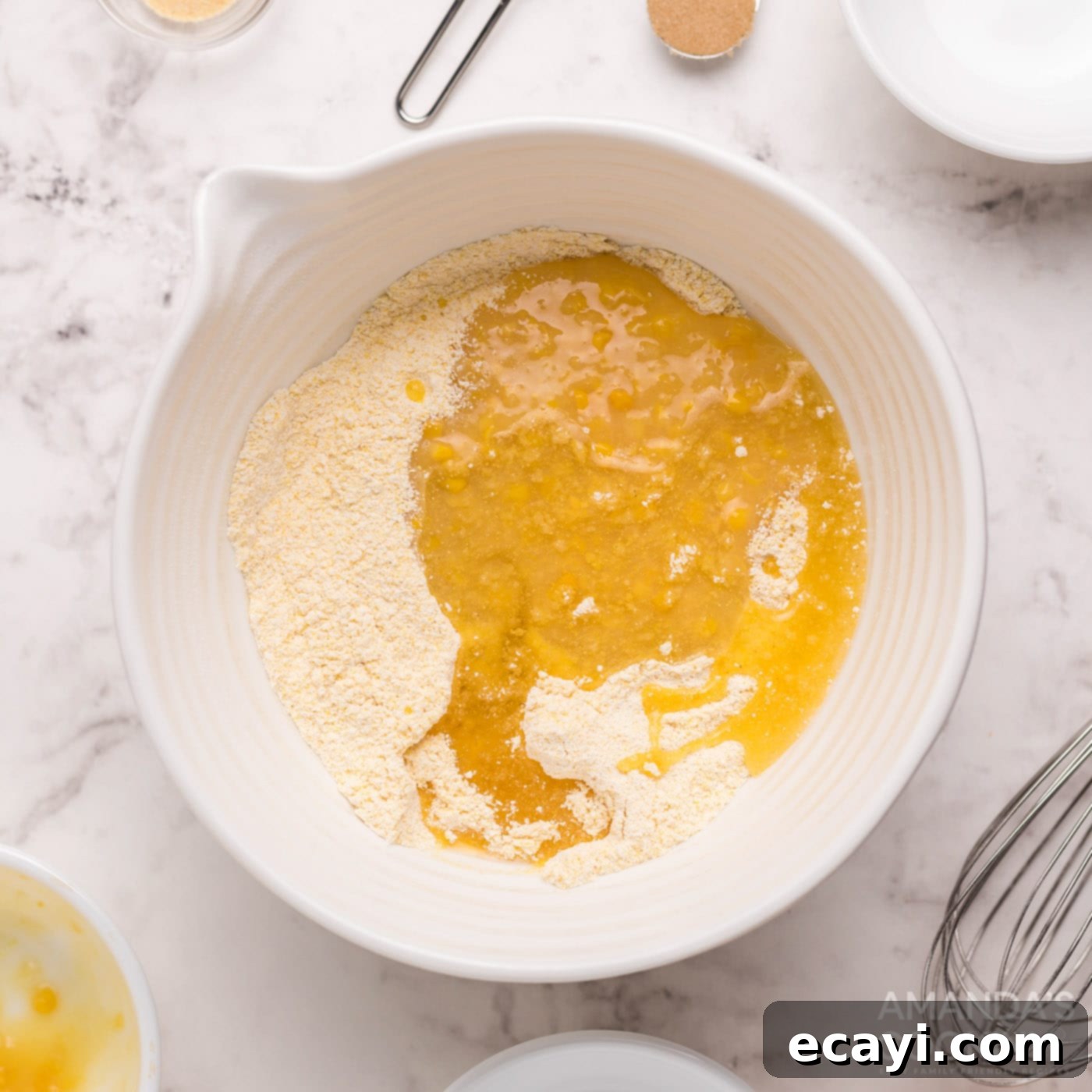 Savory Cornbread Sloppy Joe Bites 6 Cream corn and canola oil being added to the cornbread mixture in a bowl