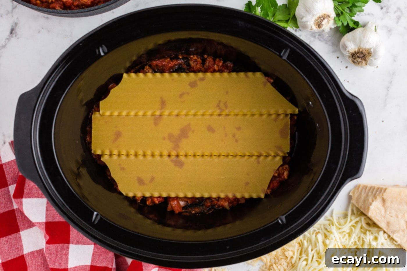 Effortless Crockpot Lasagna 8 lasagna noodles on top of meat sauce in crockpot