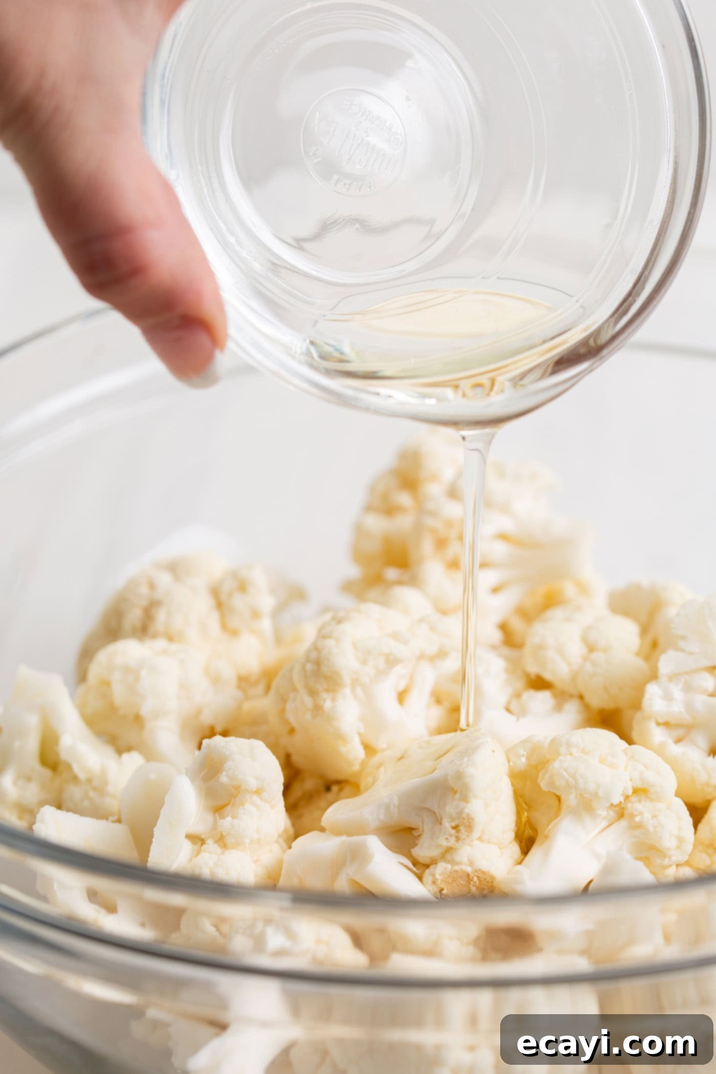 Crispy Air Fryer Cauliflower 5 Oil being drizzled over cauliflower in a bowl