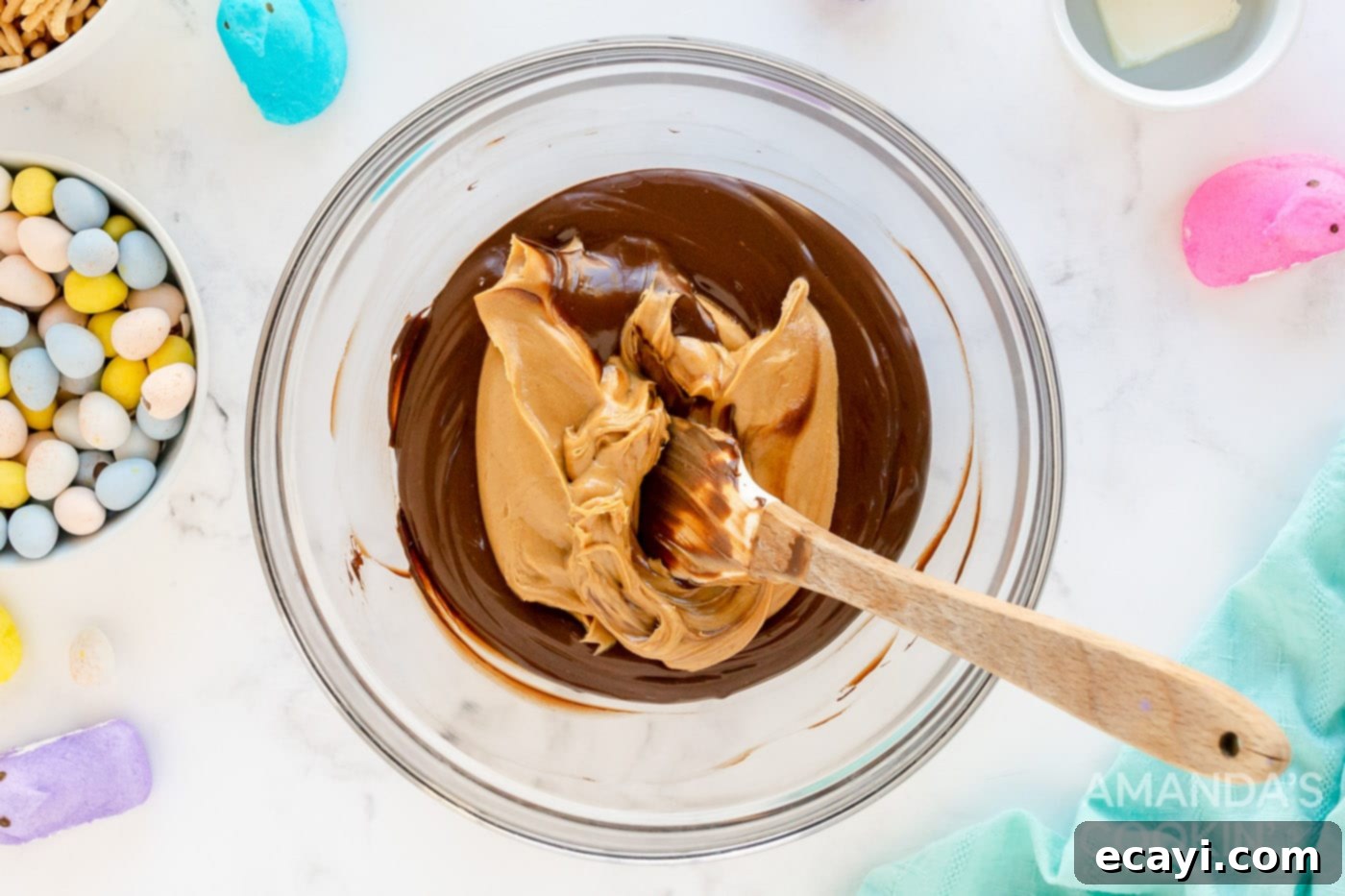 Nestled Treats 5 Peanut butter being mixed into melted chocolate in a bowl, creating a smooth, creamy mixture.