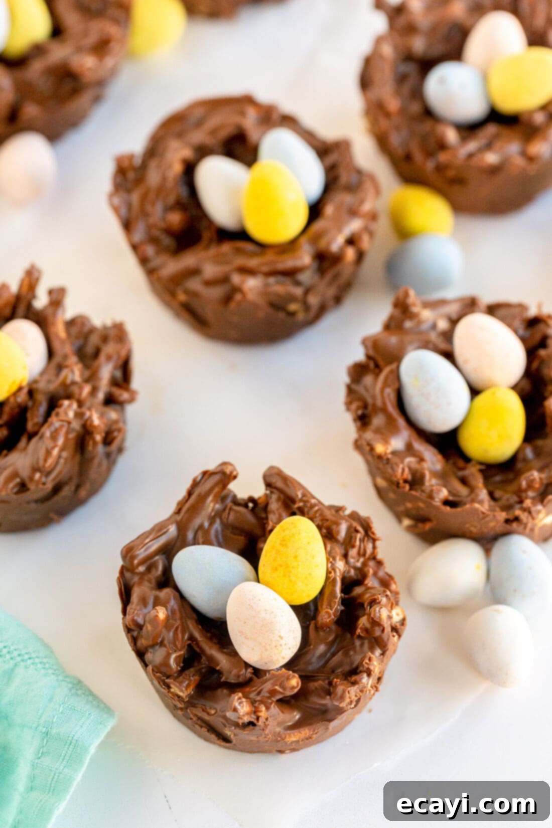 Nestled Treats 10 A close-up shot of a single bird nest cookie with three colorful candy eggs, placed on a white background.