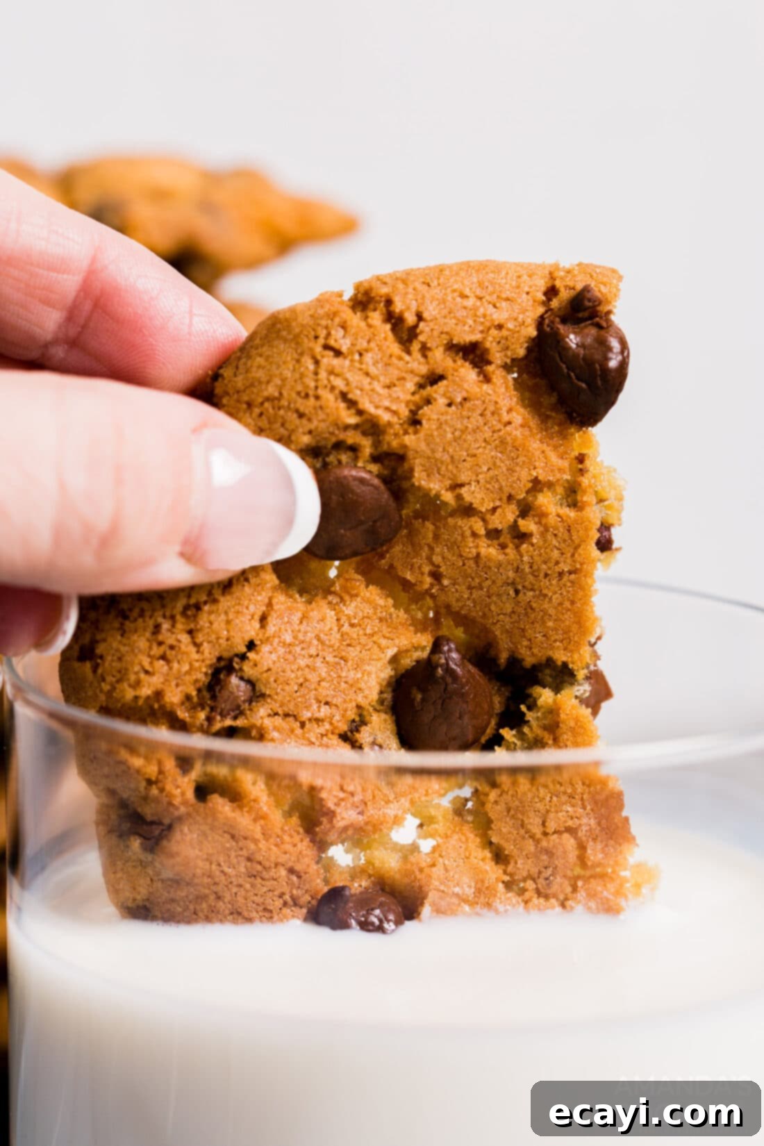 Your Air Fryer's Best Chocolate Chip Cookies 3 Close-up of a warm air fryer chocolate chip cookie being dipped into a glass of milk