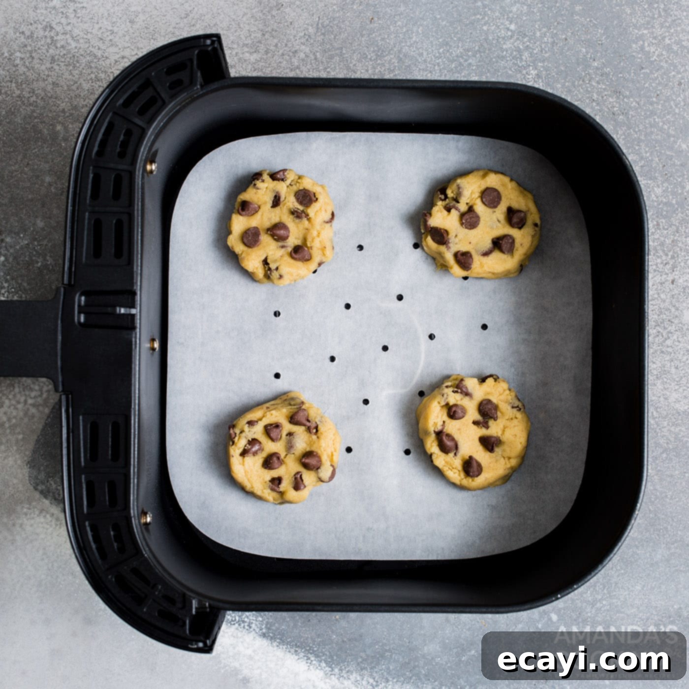 Your Air Fryer's Best Chocolate Chip Cookies 9 Four scoops of chocolate chip cookie dough placed on air fryer parchment paper in the basket