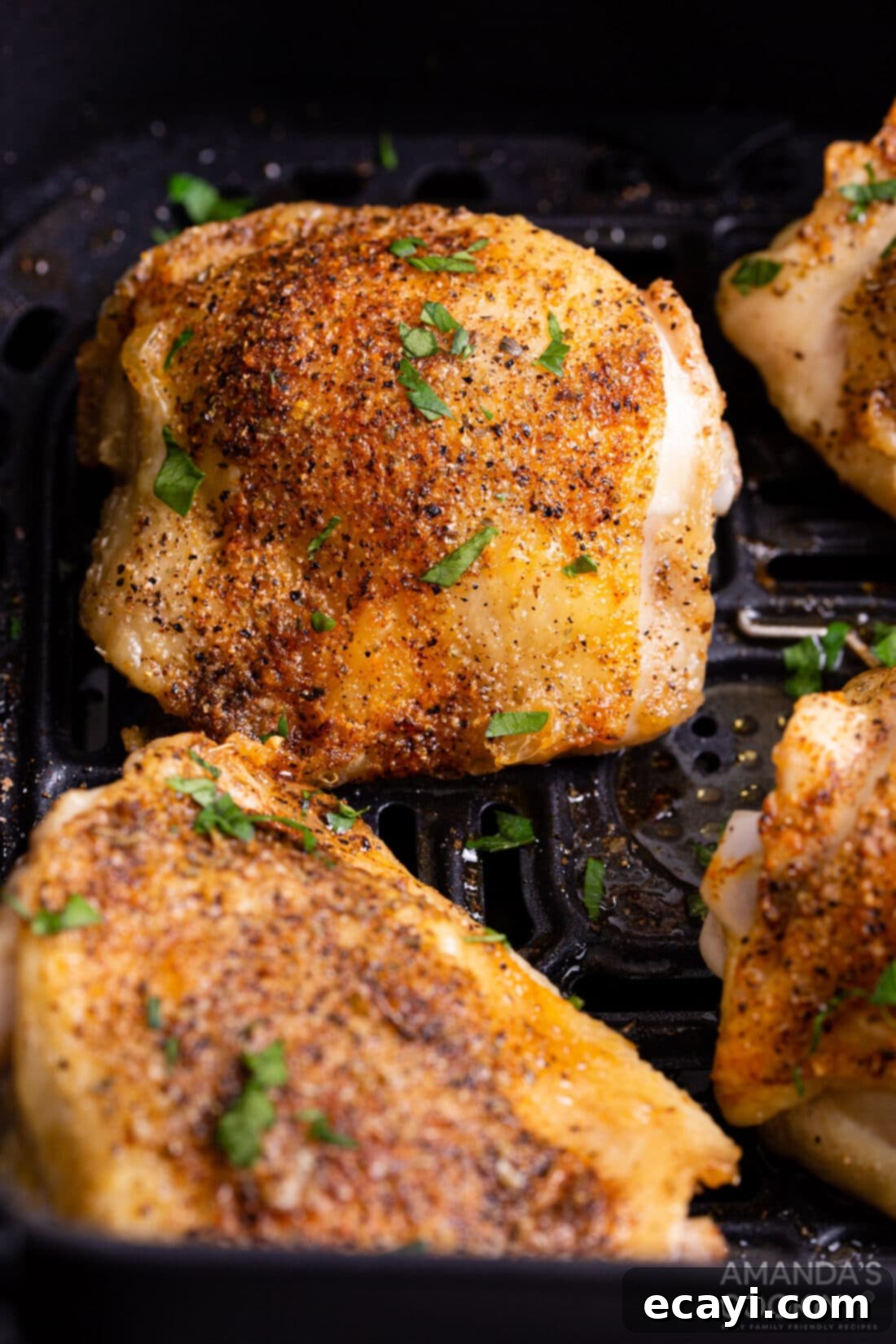 Crispy Air Fryer Chicken Thighs 2 Cooked bone-in skin-on chicken thighs in an air fryer basket, golden brown and perfectly crispy, highlighting the dish's appeal.