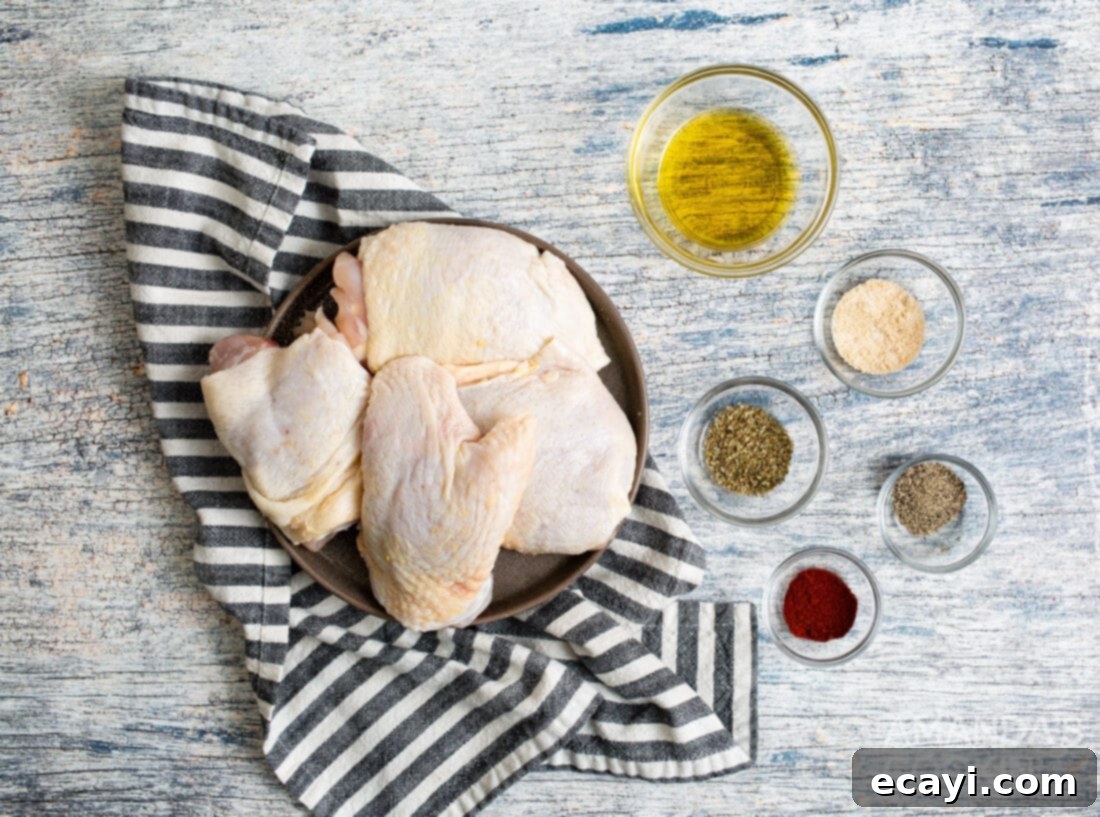 Crispy Air Fryer Chicken Thighs 4 A flat lay of all the fresh ingredients needed for air fryer chicken thighs: bone-in chicken thighs, a bottle of olive oil, and small bowls of garlic salt, paprika, marjoram, and black pepper.