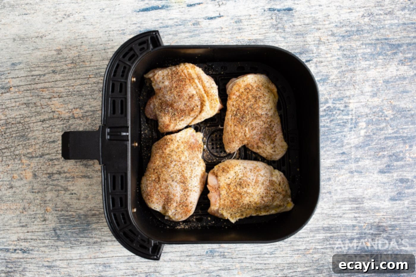Crispy Air Fryer Chicken Thighs 7 Chicken thighs placed skin side down in an air fryer basket, ready for the initial cooking phase.