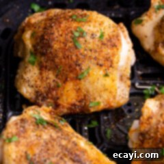 Crispy Air Fryer Chicken Thighs 10 A top-down view of a plate with two crispy air fryer chicken thighs, garnished with fresh parsley and a lemon wedge, showcasing the final delicious dish.