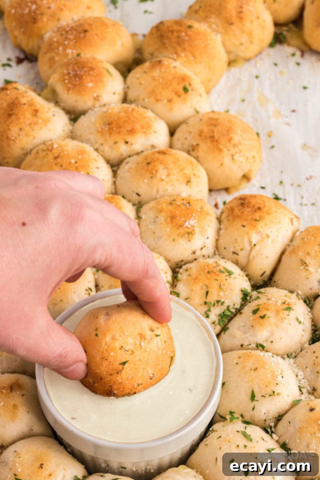 Easter Bunny Tear and Share Bread 3 A hand dipping a piece of warm, cheesy pull-apart bread into a creamy ranch sauce, highlighting the deliciousness of the Easter bunny appetizer.
