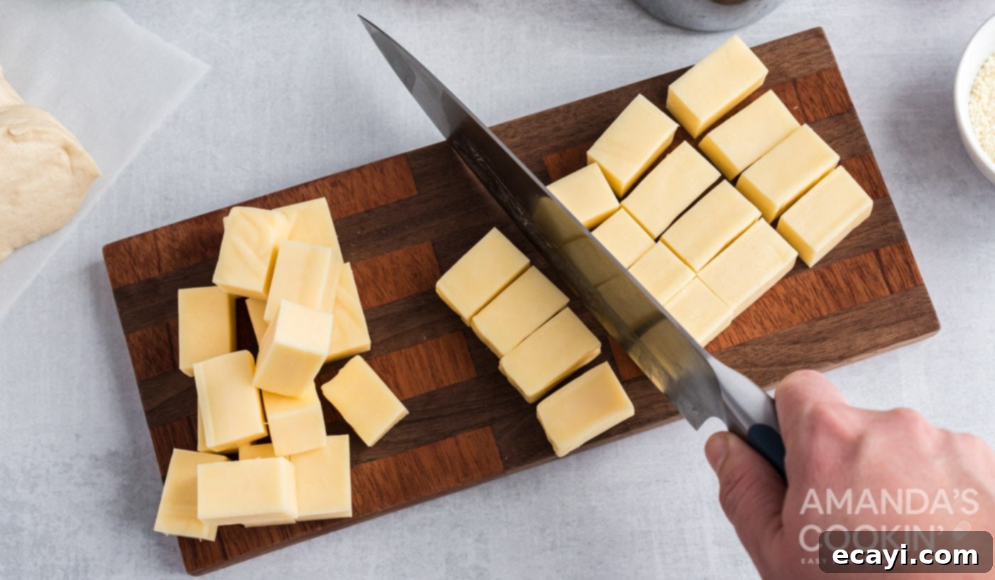 Easter Bunny Tear and Share Bread 5 A chef's knife carefully cutting a block of mozzarella cheese into small, uniform cubes, demonstrating the cheese preparation step for the Easter bunny pull apart bread.