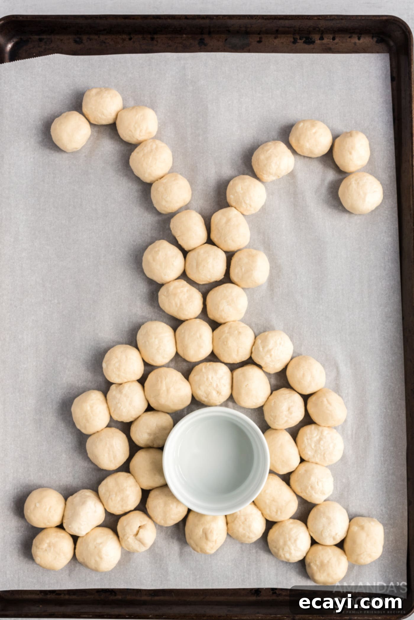 Easter Bunny Tear and Share Bread 8 Arrangement of cheese-filled biscuit dough balls on a baking sheet, forming the distinct shape of an Easter bunny, with a small ramekin placed for the tail.