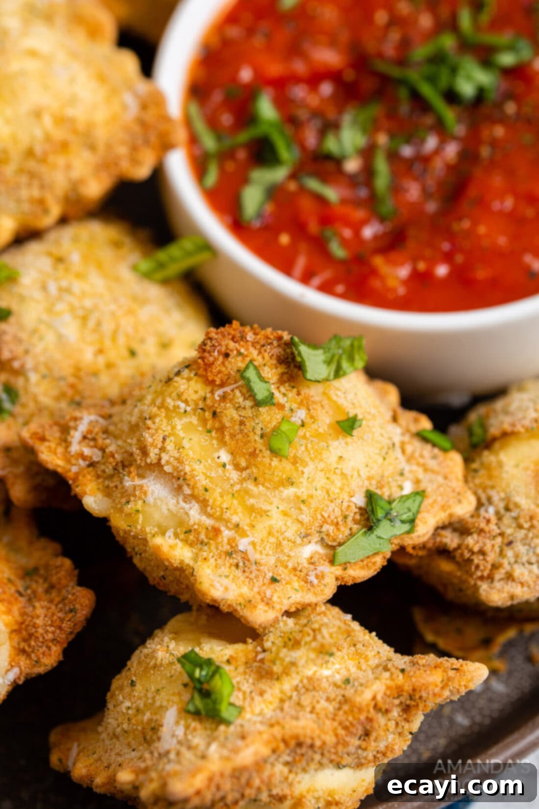 Crispy Air Fryer Ravioli 3 Air fried ravioli arranged on a plate with a small bowl of marinara for dipping