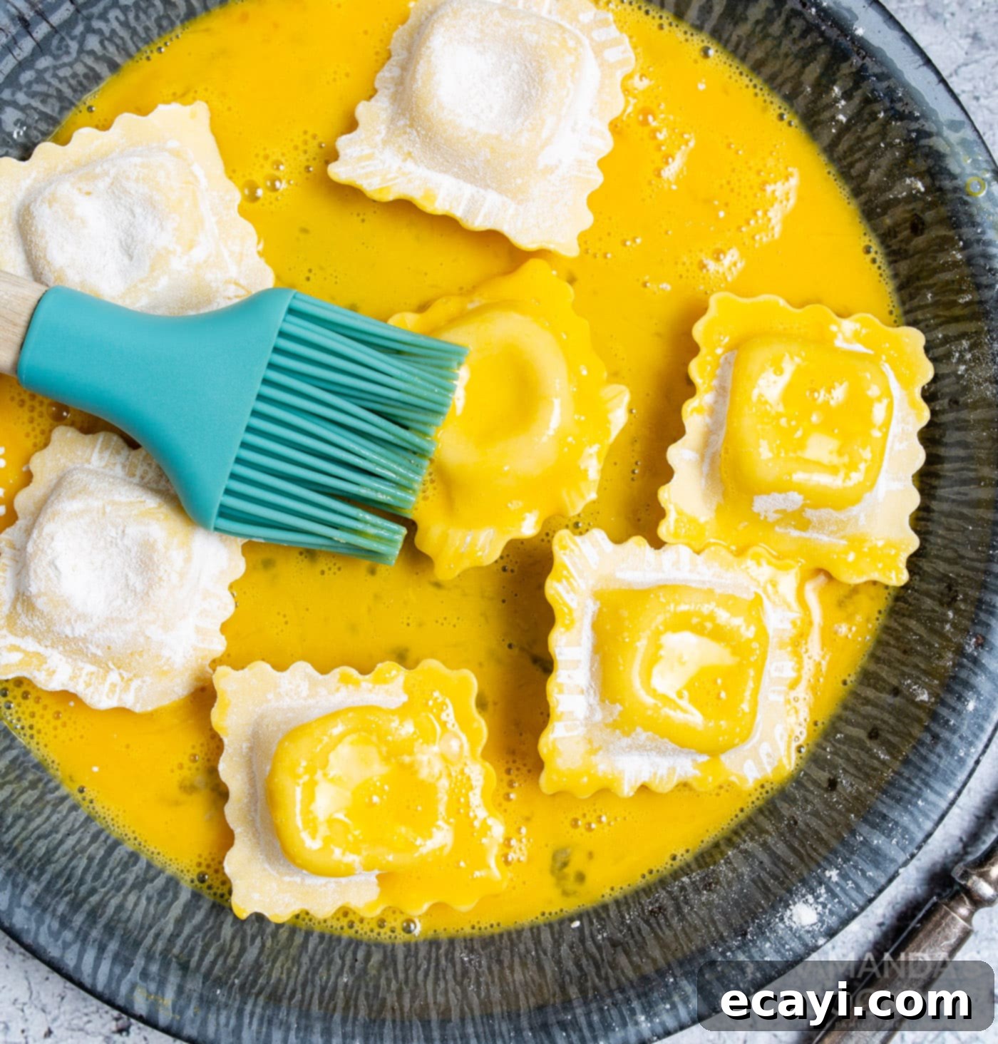 Crispy Air Fryer Ravioli 7 Chef brushing ravioli with egg wash in a bowl