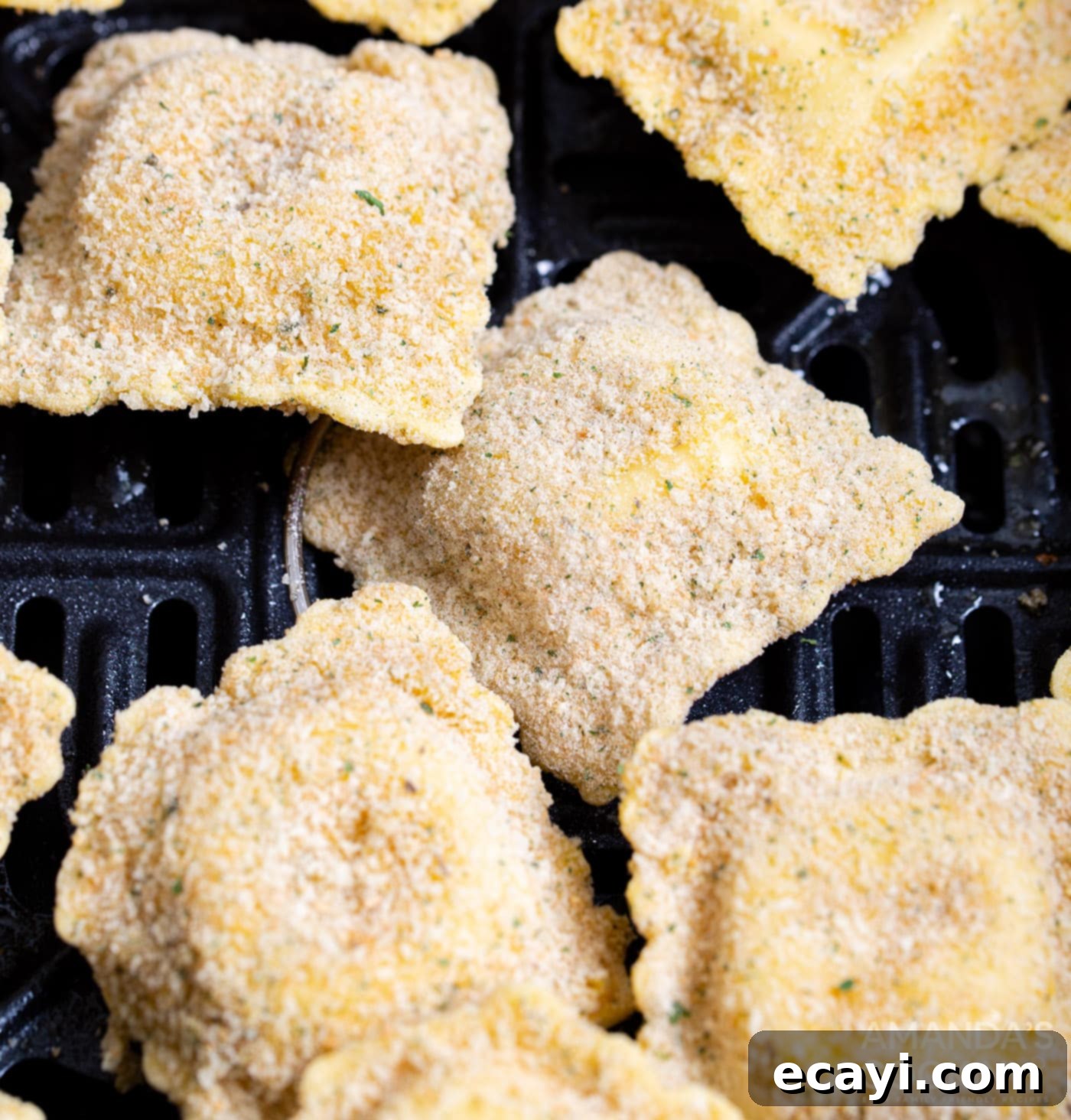 Crispy Air Fryer Ravioli 9 Air fryer basket being sprayed with non-stick spray, followed by ravioli cooking inside
