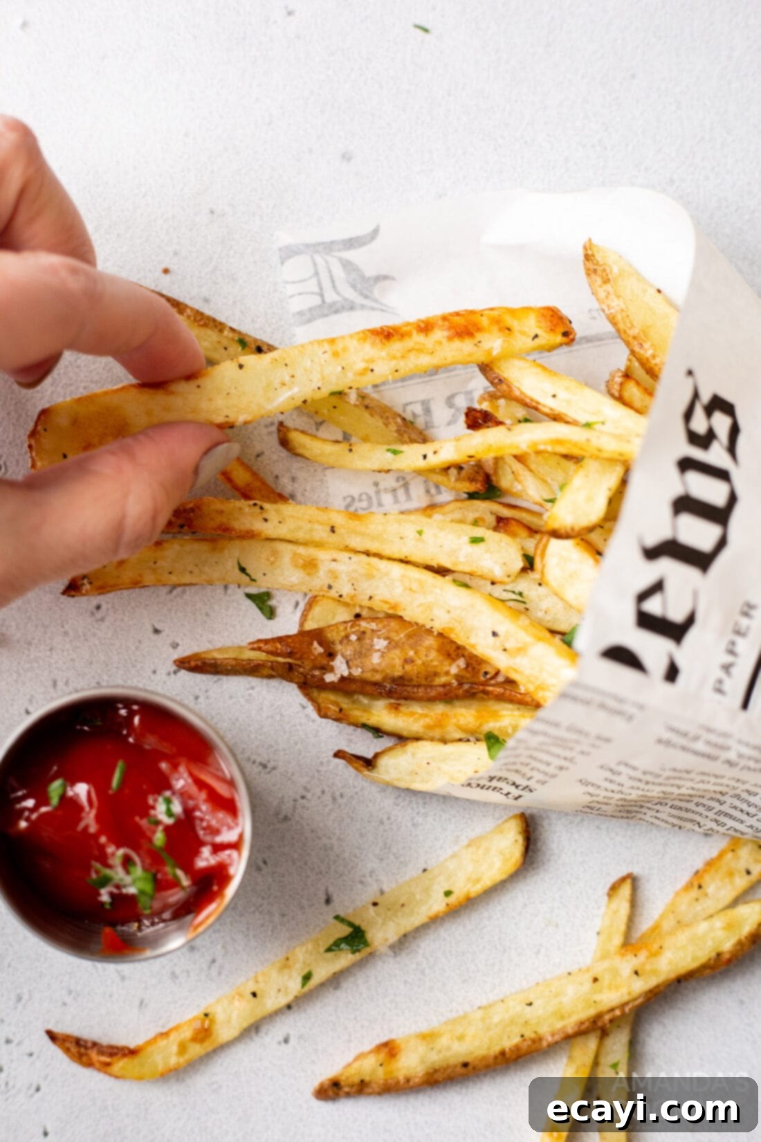 Perfectly Crispy Air Fryer Fries 3 A hand reaching for a perfectly cooked, golden air fryer french fry from a basket.