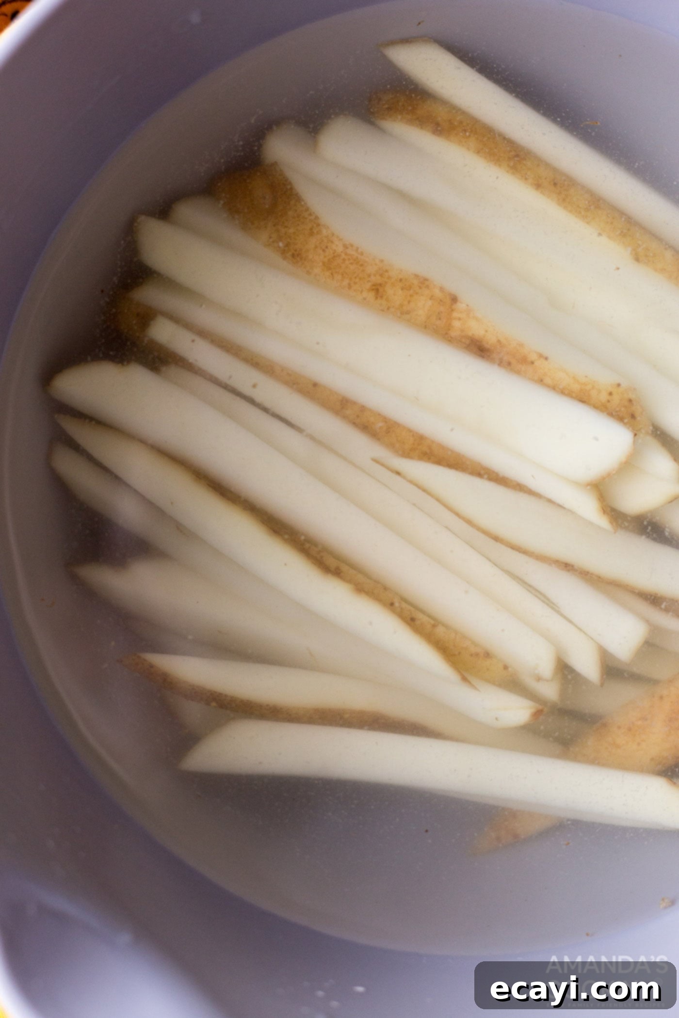 Perfectly Crispy Air Fryer Fries 5 Thinly sliced potato sticks soaking in a bowl of cold water.