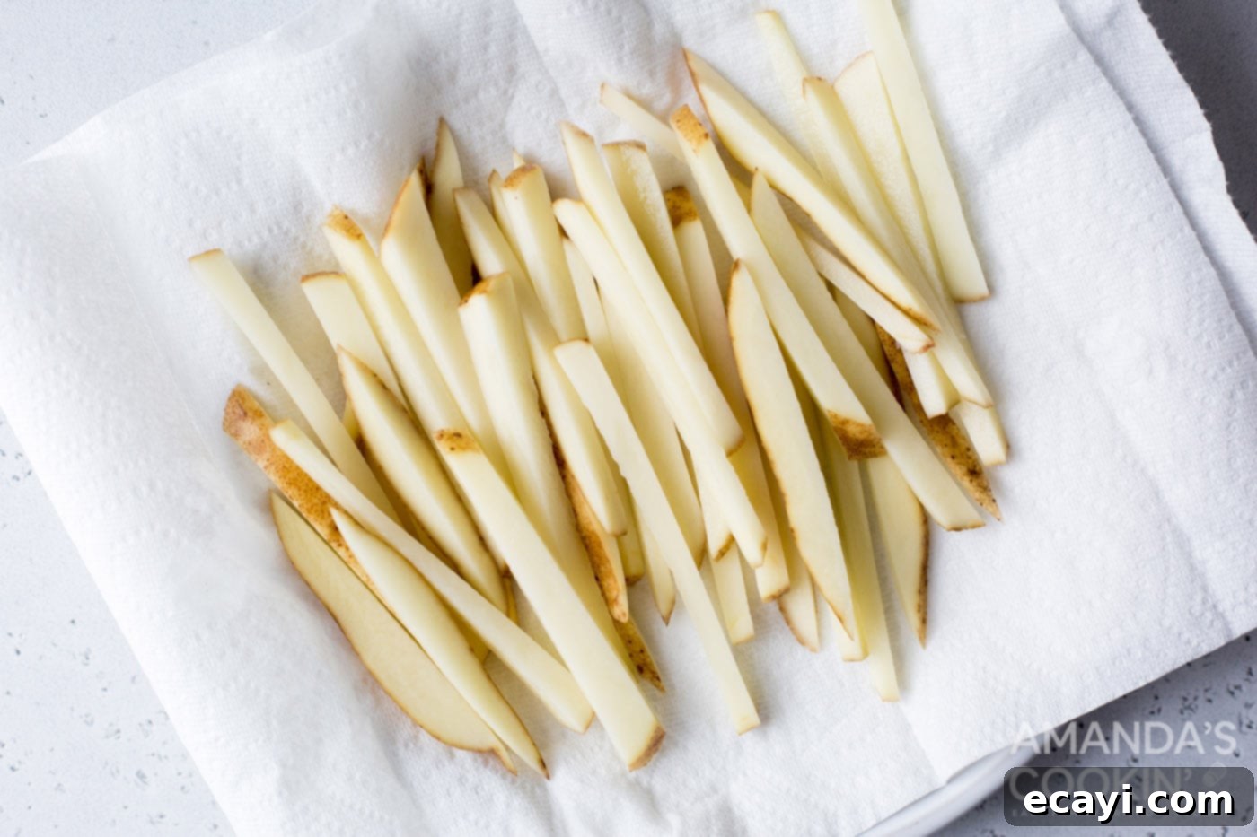 Perfectly Crispy Air Fryer Fries 6 Drained potato slices being thoroughly dried on paper towels before air frying.
