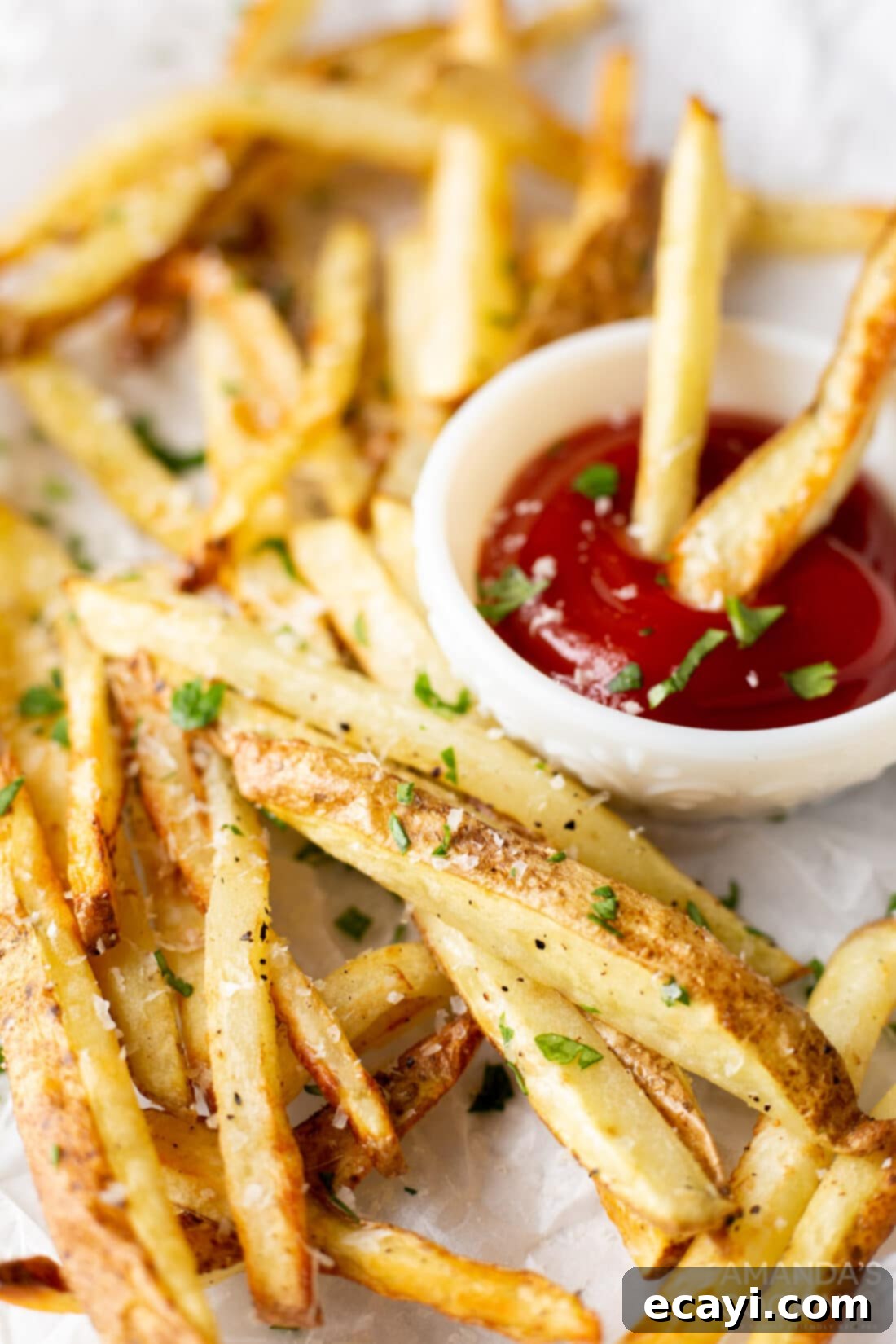Perfectly Crispy Air Fryer Fries 9 A plate of golden, crispy air fryer french fries served with a side of classic ketchup, garnished with fresh herbs.