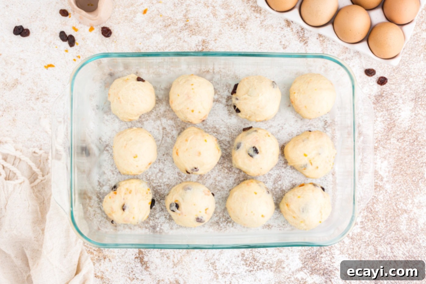 Spiced Easter Buns 14 Small dough balls arranged neatly in a greased 13x9 inch baking dish before their second rise.