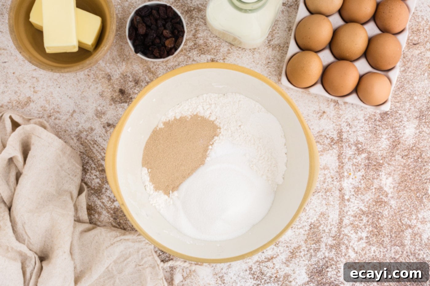 Spiced Easter Buns 5 Granulated sugar, active dry yeast, and two cups of flour are combined in a large mixing bowl, ready for the next steps in making Hot Cross Buns.