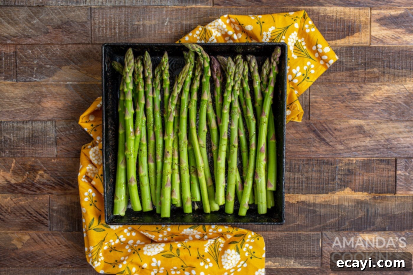 Crispy Air-Fried Asparagus 5 asparagus in a casserole dish being tossed with olive oil, salt, and pepper