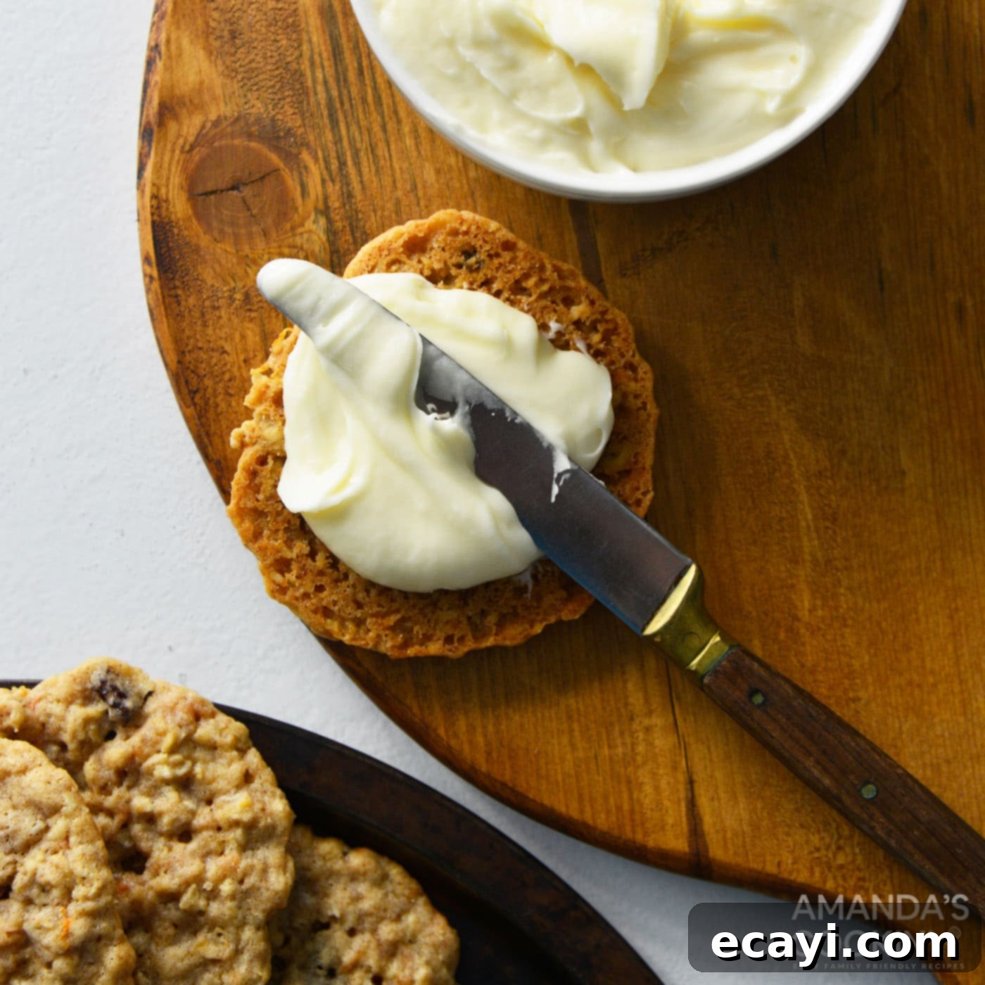 Decadent Carrot Cake Cookie Sandwiches 12 spreading cream cheese frosting onto cookie with a butter knife