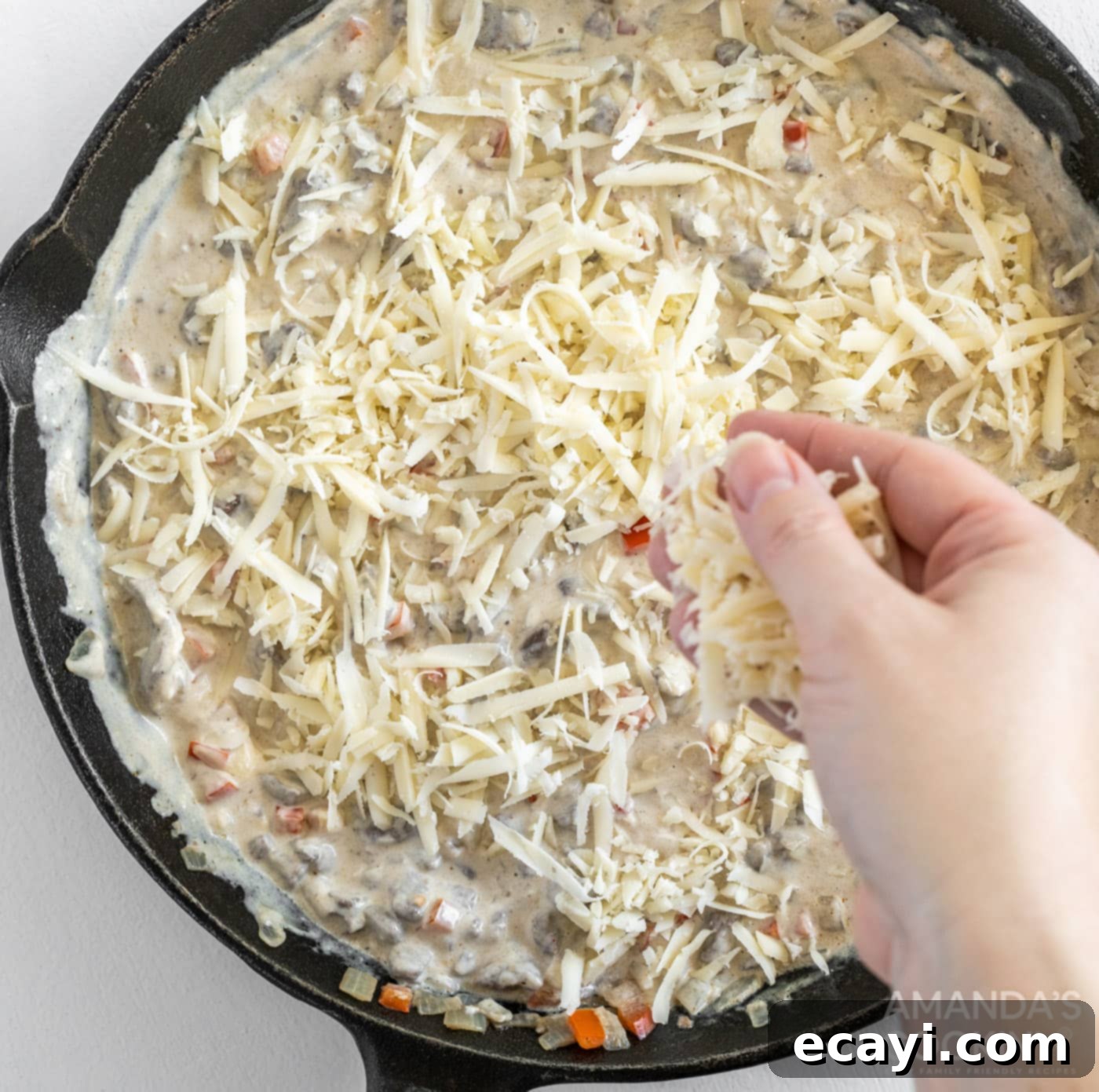 Loaded Philly Cheesesteak Dip 11 The Philly Cheesesteak Dip mixture topped with reserved cheese in a cast iron skillet, ready for the oven.
