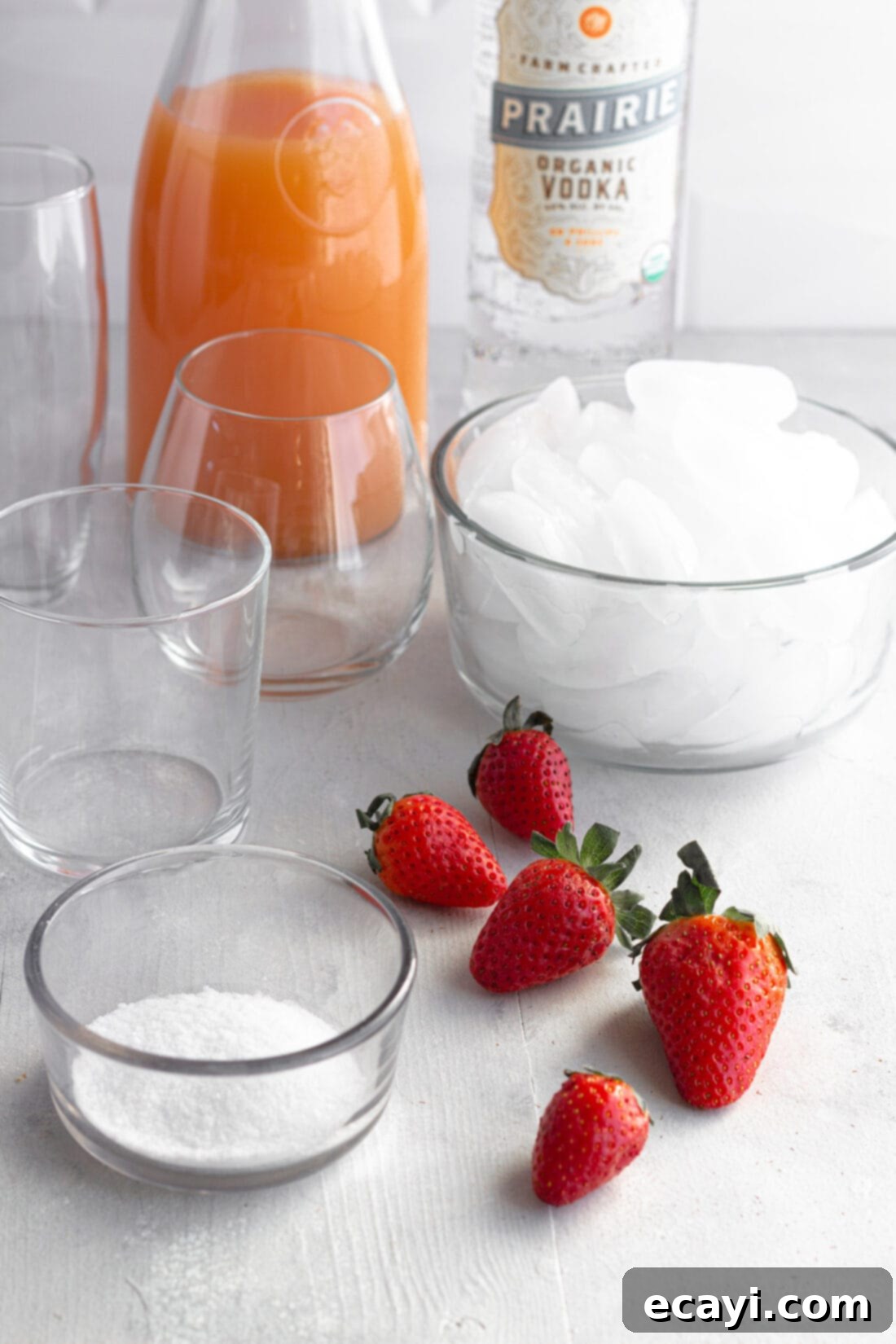 Strawberry Salty Freeze 4 Ingredients laid out for Frozen Strawberry Salty Dog Cocktails, including grapefruit juice, strawberries, and vodka