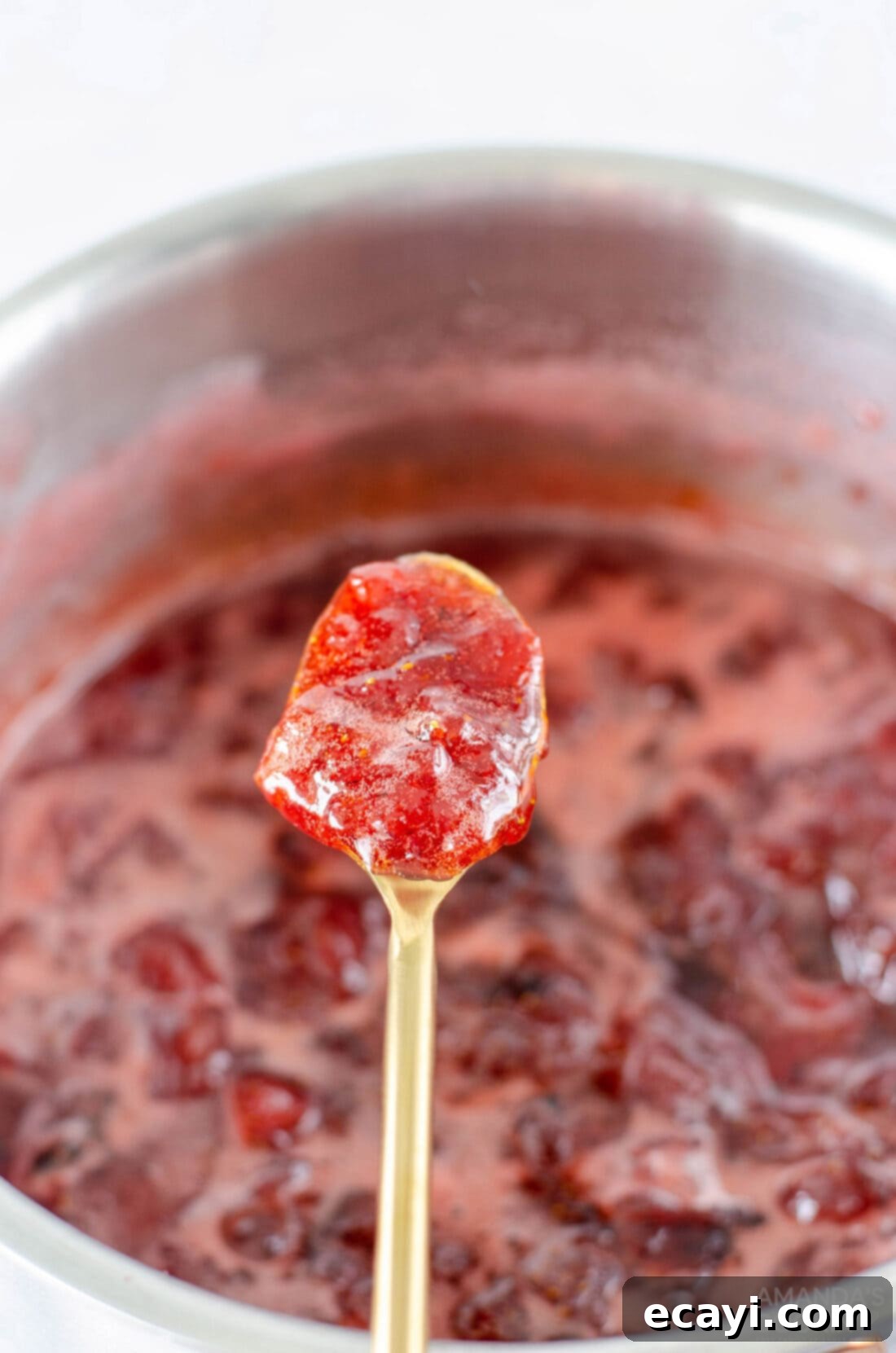 Homemade Strawberry Bliss 3 A spoon lifts a spoonful of glistening homemade strawberry jam from a simmering pot, showing its rich texture