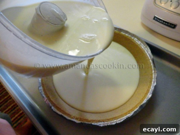 lemonade-cheesecake-step-2 A photo of the ingredients for lemonade cheesecake in a food processor being poured into a graham cracker pie crust.