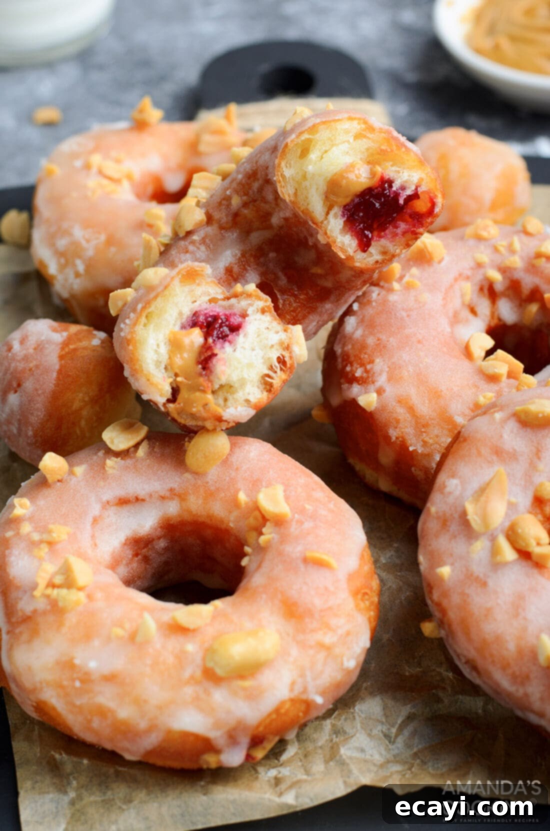 Peanut Butter and Jelly Donut Perfection 2 Peanut Butter & Jelly Donuts in half showing the inside, revealing warm peanut butter and vibrant raspberry jelly