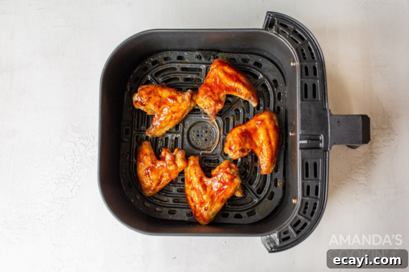 Crispy Air-Fried Wings 9 chicken wings in air fryer basket with sauce