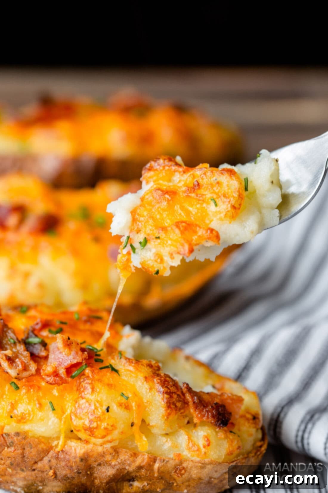 Golden Crispy Air Fryer Twice Baked Potatoes 3 Fork lifting a piece of a fluffy, stuffed air fryer twice baked potato