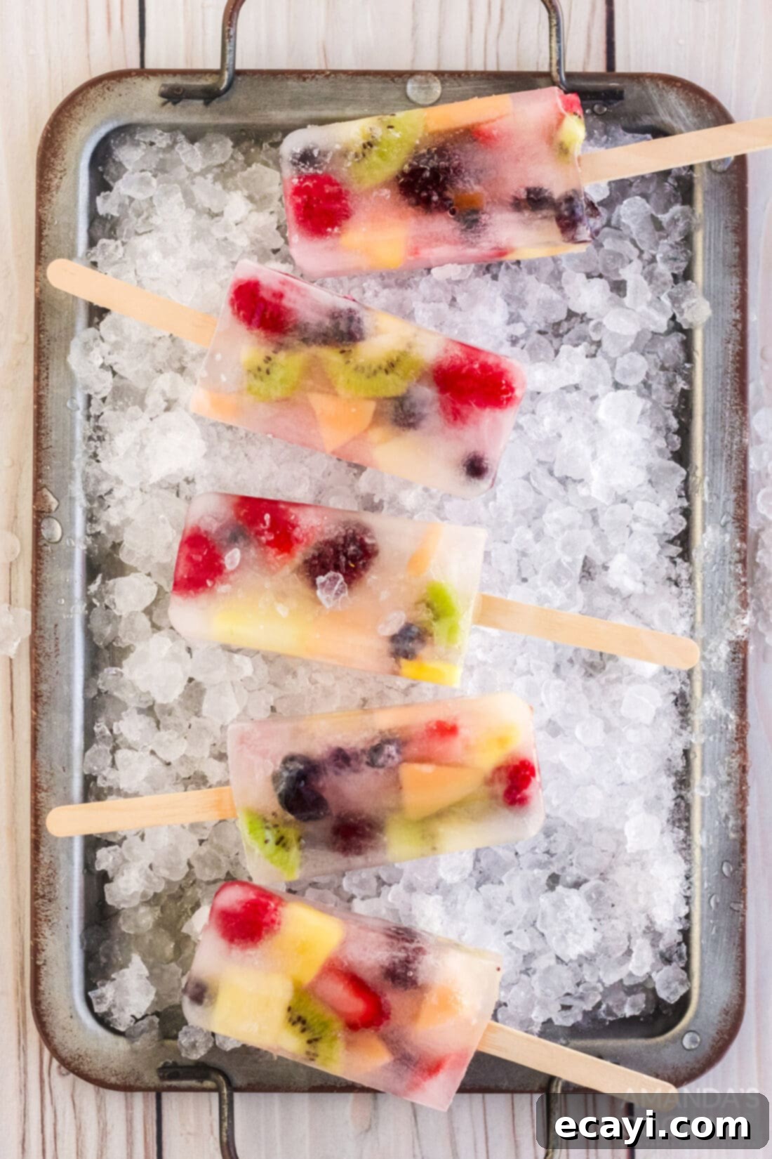 Refreshing Fruit Treats 3 Assortment of homemade fruit popsicles on a bed of ice cubes, showcasing different fruit combinations and colors, ready to be enjoyed.