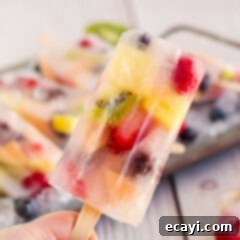 Refreshing Fruit Treats 9 A top-down view of a colorful fruit popsicle, showcasing the layers of fruit and ice, on a white background.
