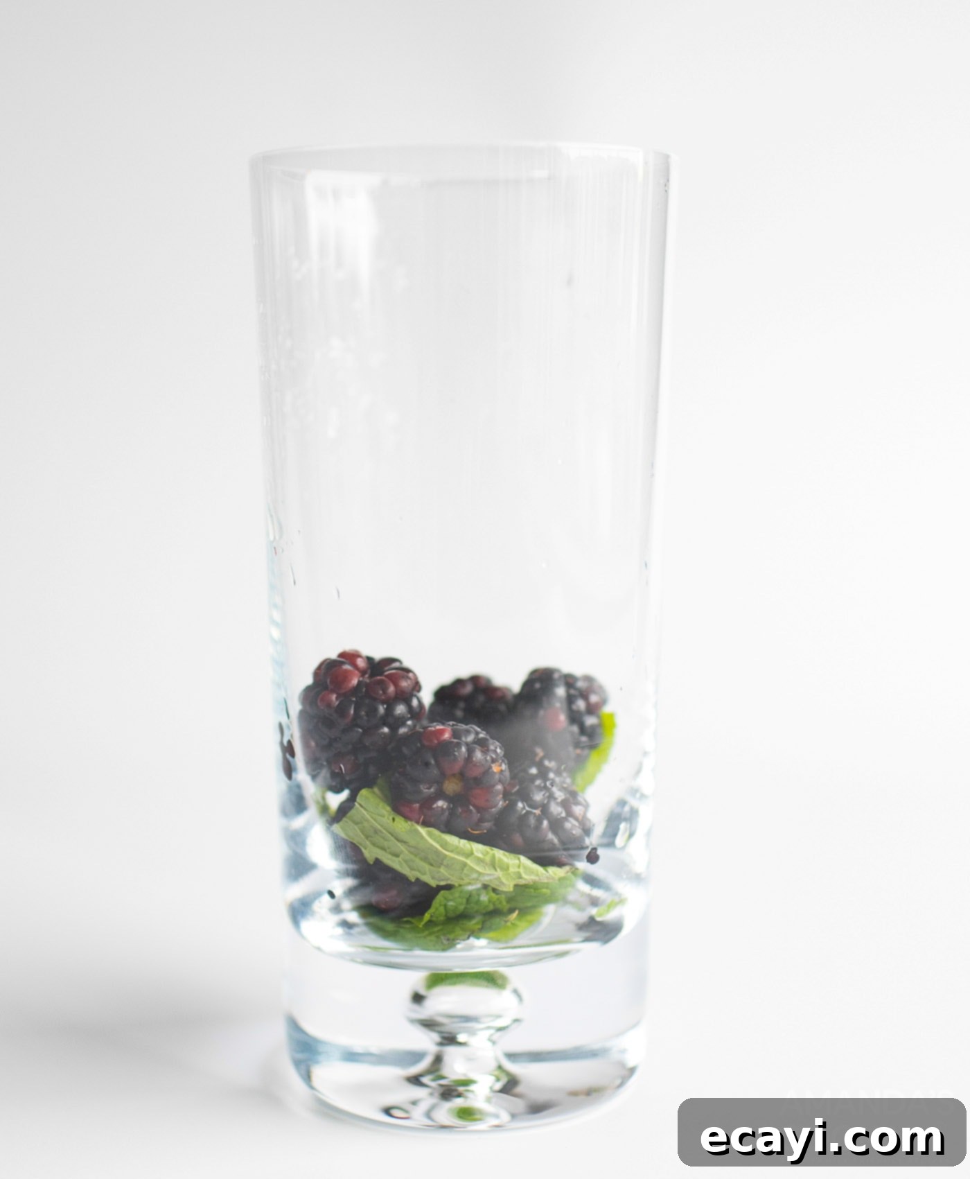 Midnight Berry Mojito 5 Blackberries and mint leaves freshly muddled in the bottom of a tall glass, ready for the next step