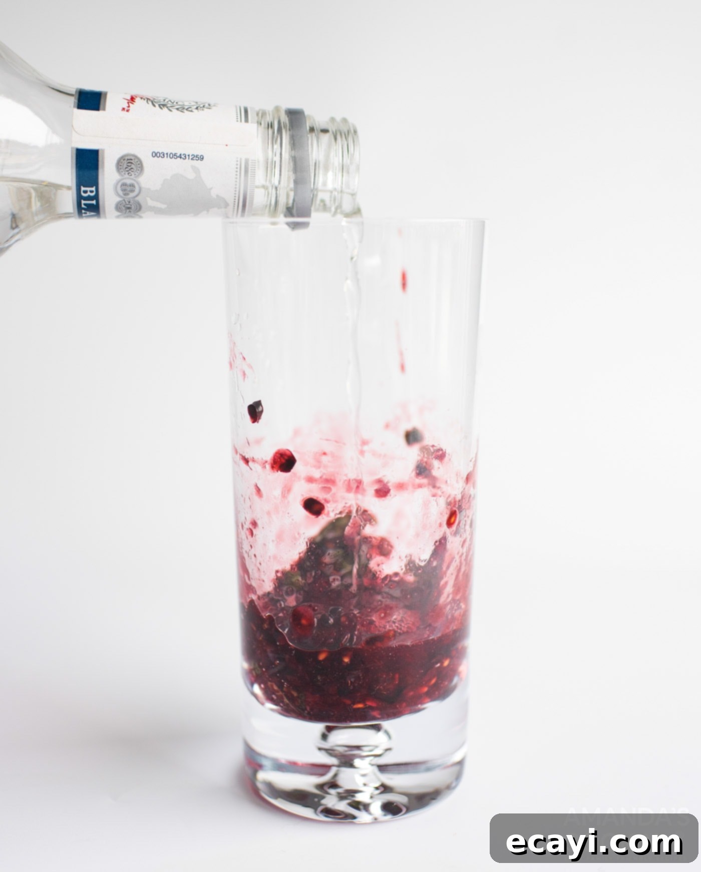 Midnight Berry Mojito 6 Pouring white rum into a tall glass with muddled blackberries, mint, and citrus