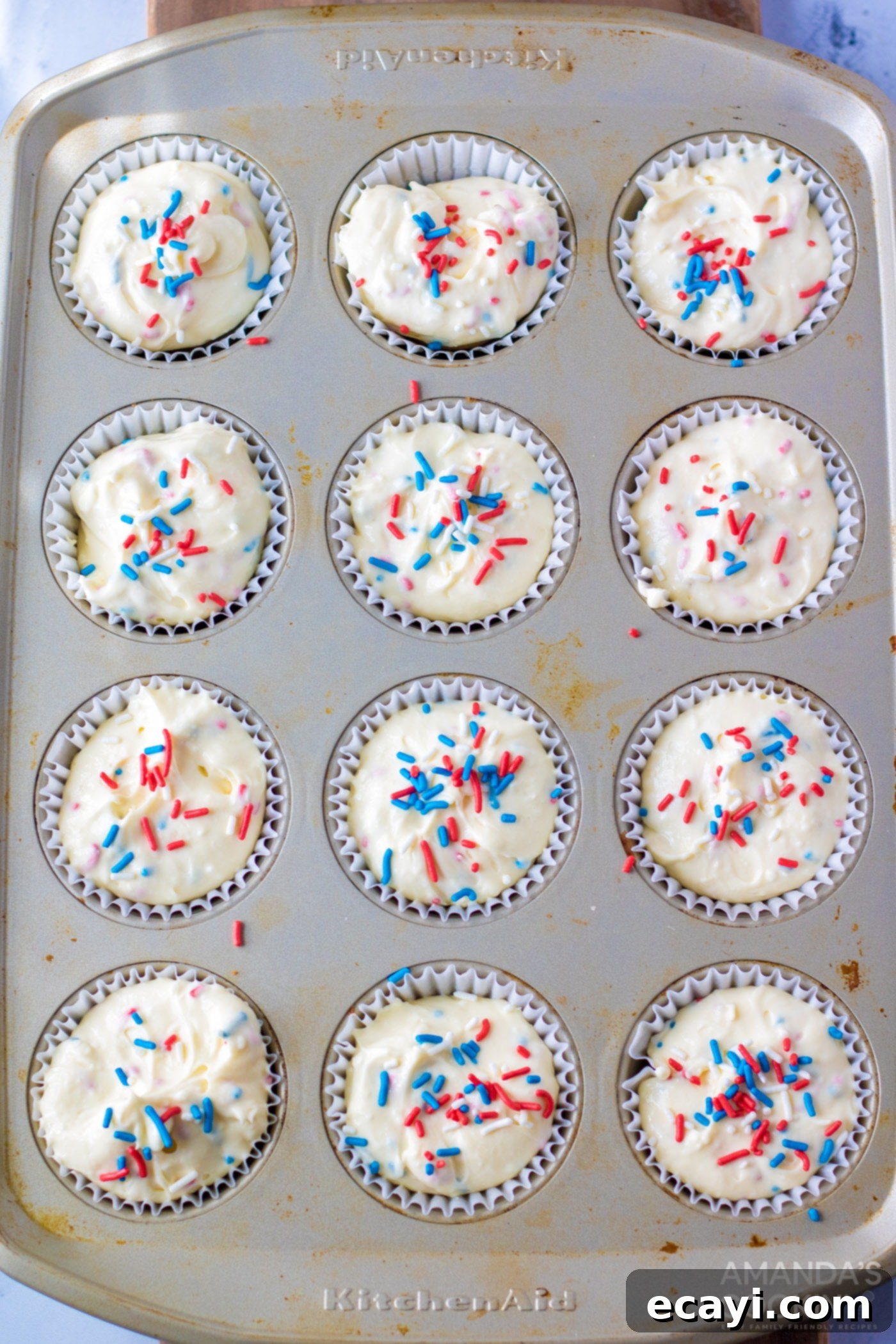 Stars and Stripes Cheesecake Bites 7 Mini cheesecake batter in a muffin tin with sprinkles on top, ready for baking