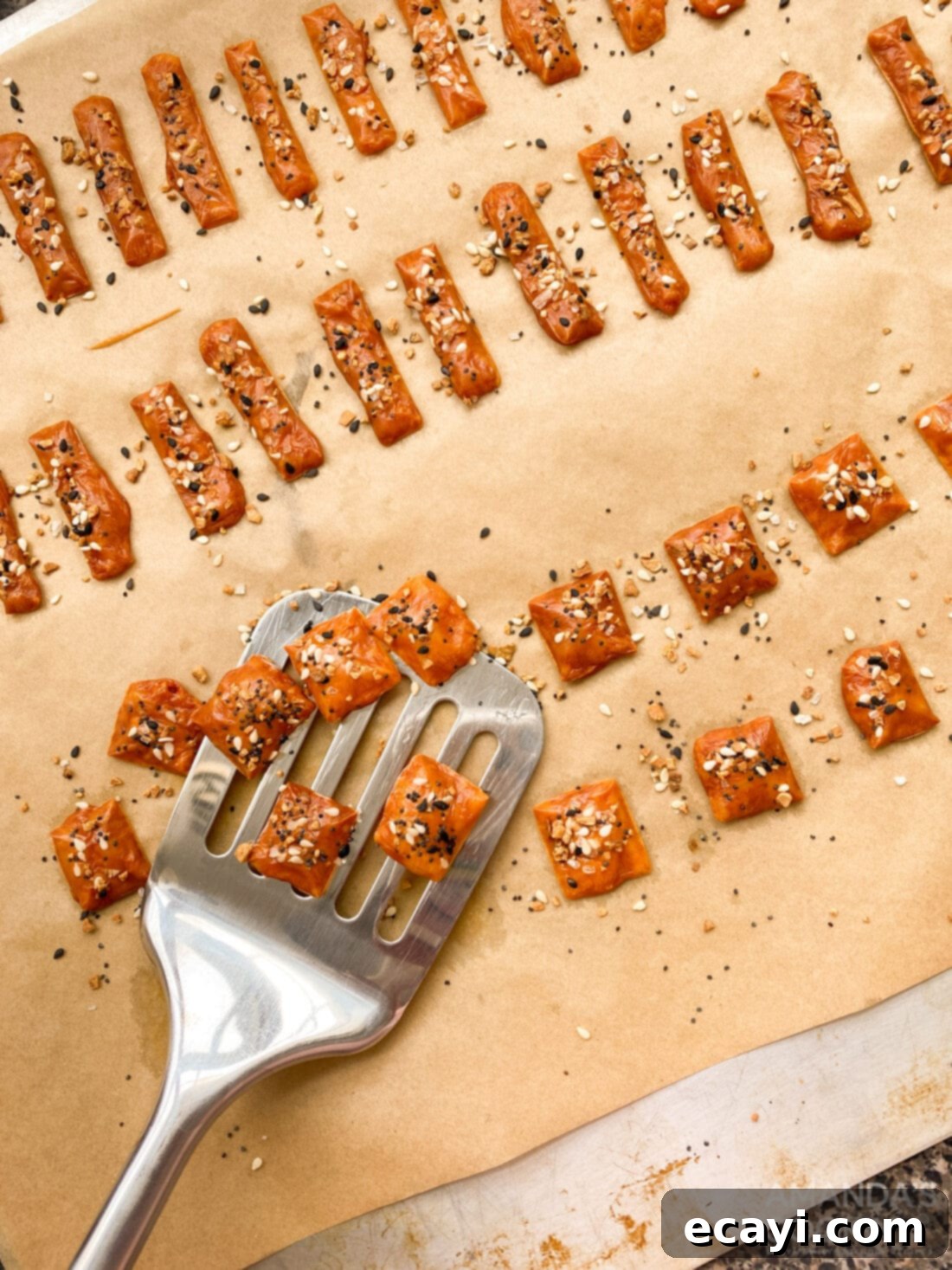 Crunchy Keto Cheese Bites 3 A spatula gently lifting perfectly baked, golden keto cheese crackers from a parchment-lined baking sheet, showcasing their crisp texture.
